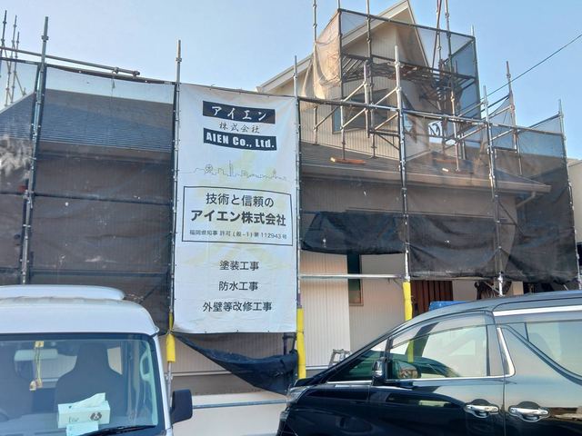足場と「技術と信頼の アイエン株式会社」の工事看板を掲げた施工現場
