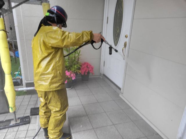 防護服を着てエントランスまわりを特殊塗装する職人